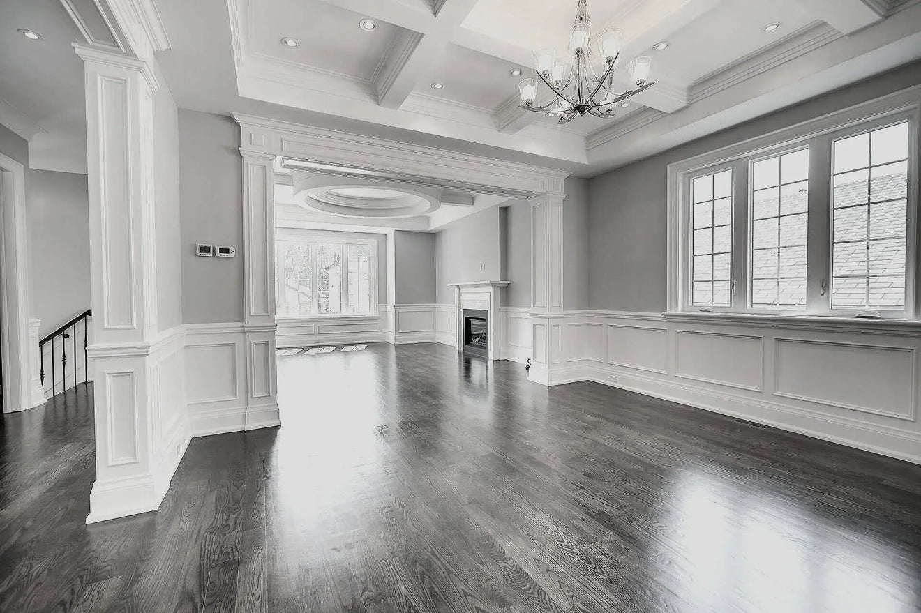 Large, empty room with high ceilings, wooden flooring, and a chandelier.